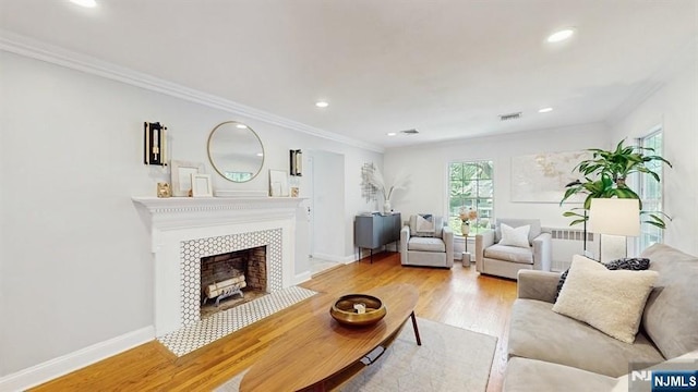 living room featuring visible vents, a tile fireplace, wood finished floors, ornamental molding, and recessed lighting