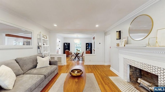 living area featuring crown molding, recessed lighting, wood finished floors, and a tiled fireplace