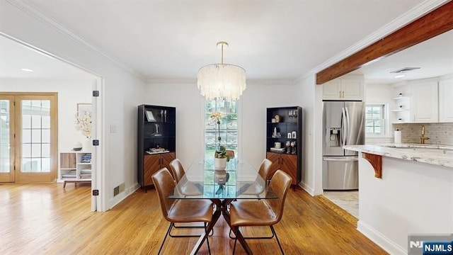 dining room with baseboards, light wood finished floors, crown molding, and a chandelier