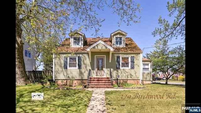 new england style home featuring fence, a front yard, and entry steps