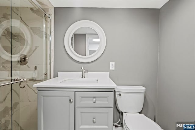 full bathroom with toilet, a marble finish shower, and vanity