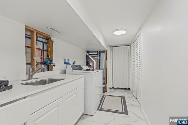 washroom with visible vents, washer and dryer, marble finish floor, and a sink