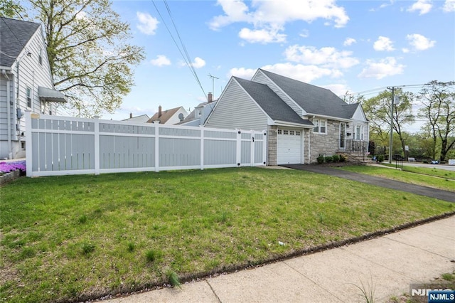 view of side of home featuring fence, driveway, a yard, and an attached garage
