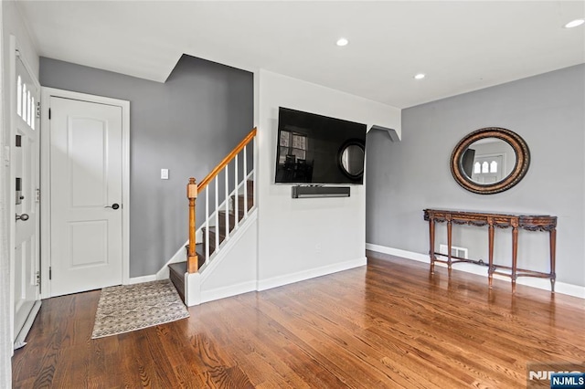entrance foyer featuring wood finished floors, visible vents, baseboards, and stairs