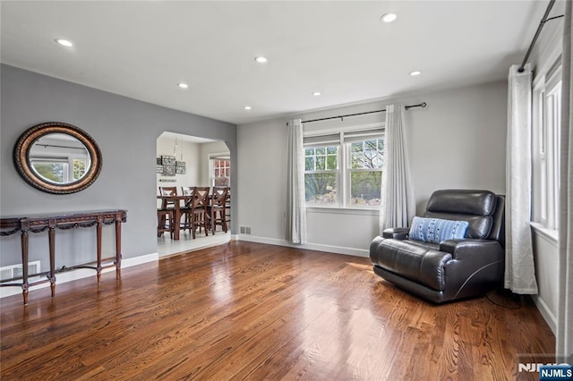 living area with recessed lighting, arched walkways, wood finished floors, baseboards, and visible vents