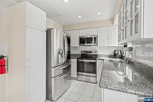 kitchen with white cabinetry, tasteful backsplash, a sink, stainless steel appliances, and light tile patterned flooring