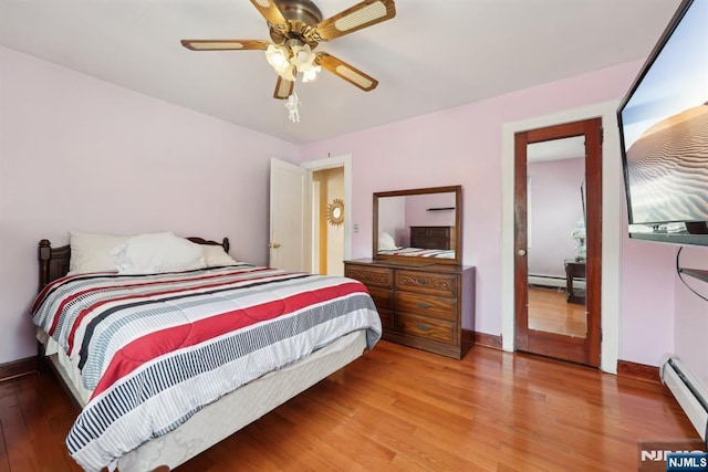 bedroom featuring wood finished floors, ceiling fan, baseboard heating, and baseboards