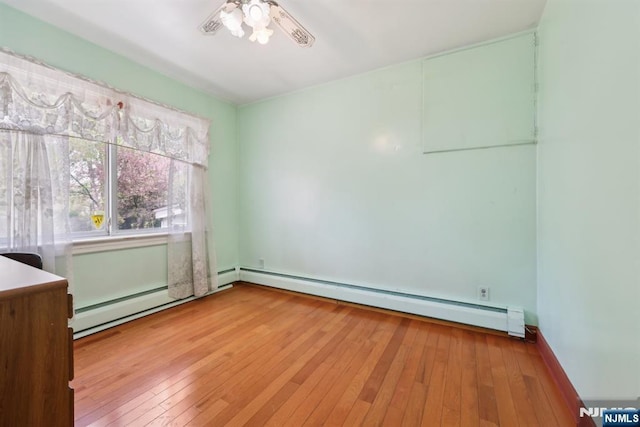 spare room with ceiling fan, hardwood / wood-style flooring, and a baseboard radiator