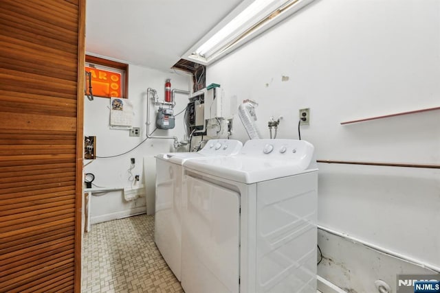 clothes washing area with washing machine and dryer, laundry area, and baseboards