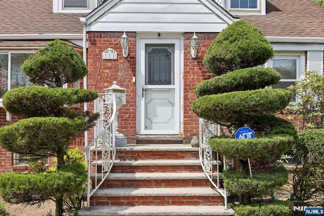 property entrance with brick siding and roof with shingles