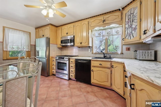 kitchen with a sink, decorative backsplash, light tile patterned floors, a ceiling fan, and appliances with stainless steel finishes