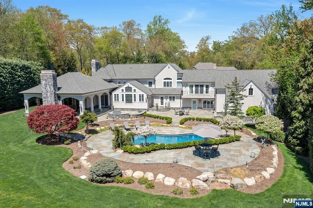 21 Birchwood, Old Tappan, NJ 07675 - rear view of house featuring a patio area, a yard, an outdoor pool, a chimney, and a balcony