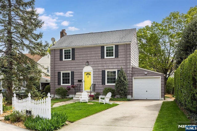 colonial home with driveway, a chimney, a front yard, fence, and a garage