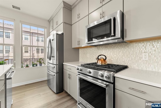 4 Arnold Dr, Wood Ridge, NJ 07075 - kitchen featuring light wood-style floors, light countertops, stainless steel appliances, tasteful backsplash, and visible vents