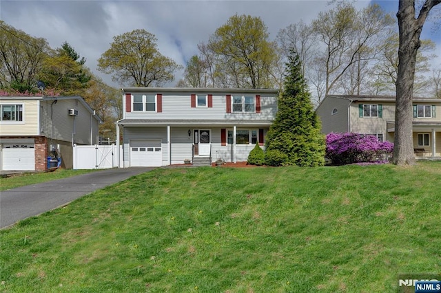 traditional home featuring aphalt driveway, a gate, a front yard, an attached garage, and fence