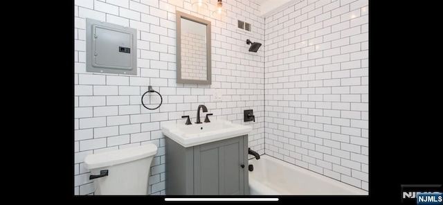 full bath featuring vanity, toilet, tile walls, shower / tub combination, and electric panel