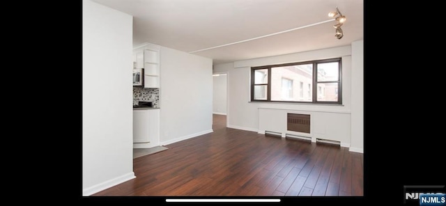unfurnished living room featuring baseboards and dark wood-style flooring