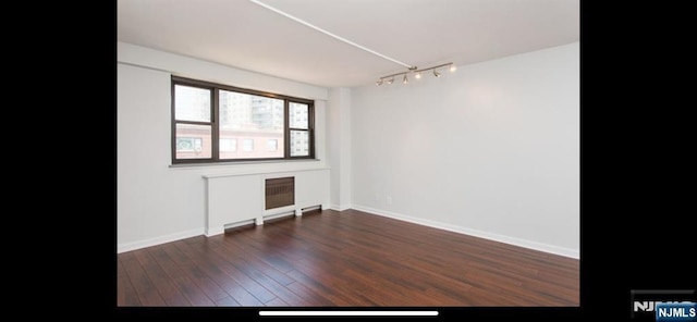 unfurnished room featuring track lighting, baseboards, and wood finished floors