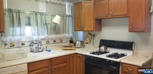 kitchen with brown cabinetry, white dishwasher, gas stove, and a sink