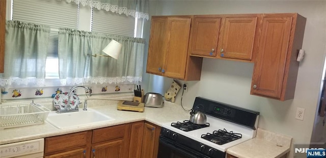 kitchen with white appliances, light countertops, brown cabinetry, and a sink