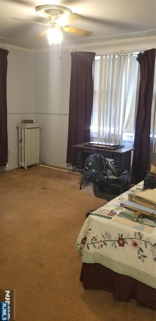 carpeted bedroom featuring a ceiling fan and crown molding