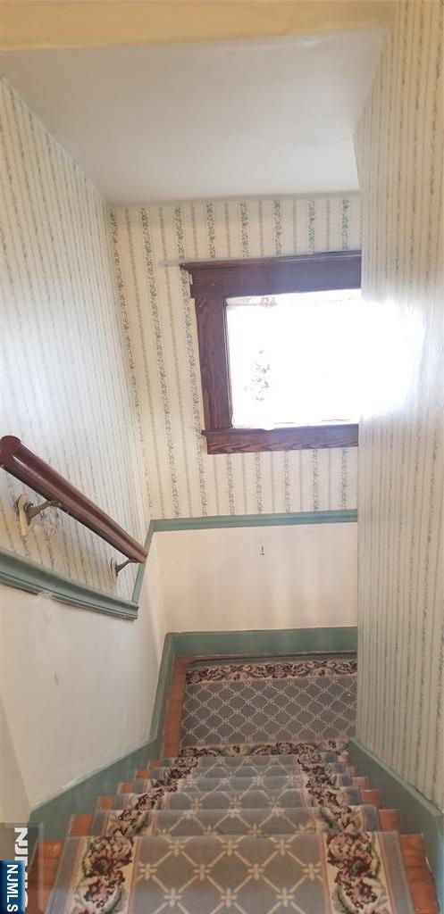 stairway featuring wallpapered walls
