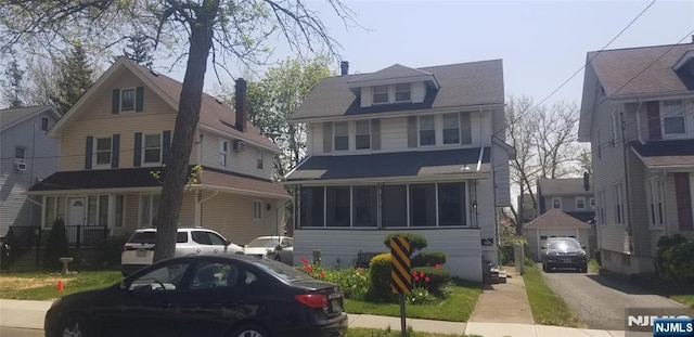 traditional style home with driveway, a detached garage, and an outbuilding