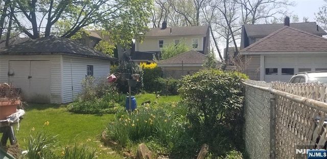 exterior space featuring fence, a garage, a storage unit, and an outbuilding