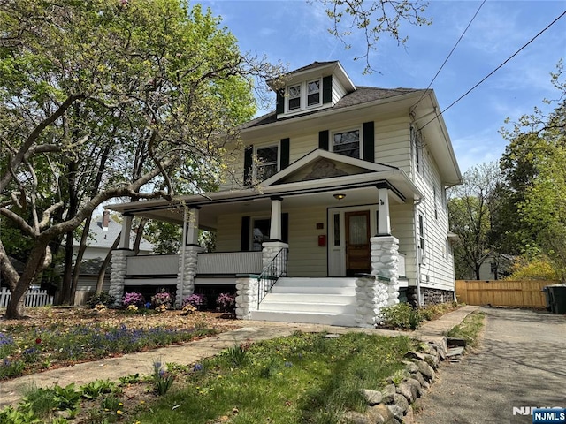 traditional style home with a porch and fence