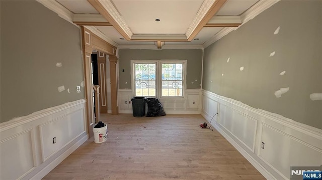 corridor featuring ornamental molding, a decorative wall, light wood-style flooring, and wainscoting