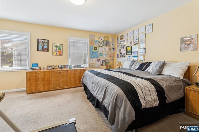 bedroom with baseboards and light colored carpet