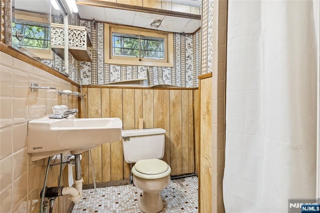 full bath with a wainscoted wall, a healthy amount of sunlight, toilet, and wallpapered walls