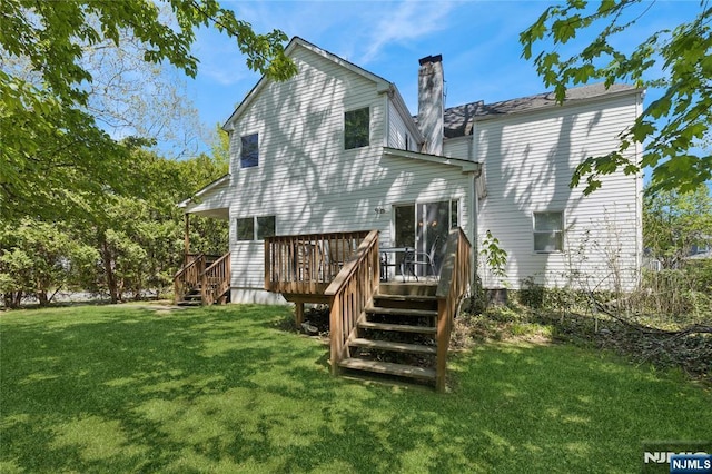 back of property with a lawn, a wooden deck, stairs, and a chimney