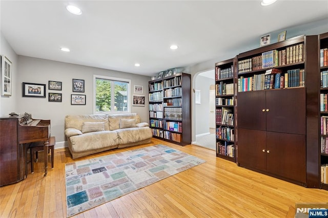 living area featuring recessed lighting, arched walkways, baseboards, and wood finished floors