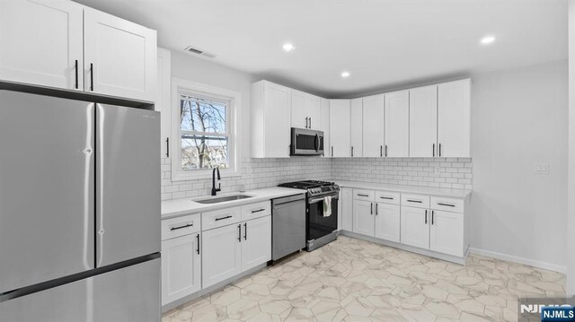 kitchen featuring visible vents, light countertops, white cabinets, a sink, and stainless steel appliances