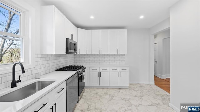 kitchen featuring a sink, light countertops, stainless steel microwave, gas range oven, and dishwashing machine