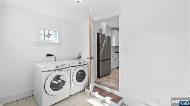 washroom featuring laundry area, baseboards, light tile patterned floors, and washer and dryer