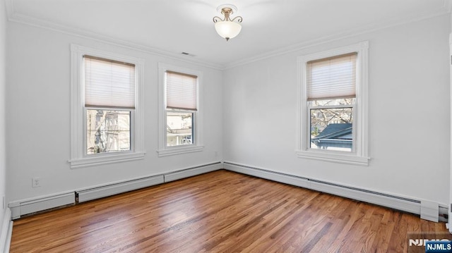 unfurnished room featuring ornamental molding, baseboard heating, wood finished floors, and visible vents