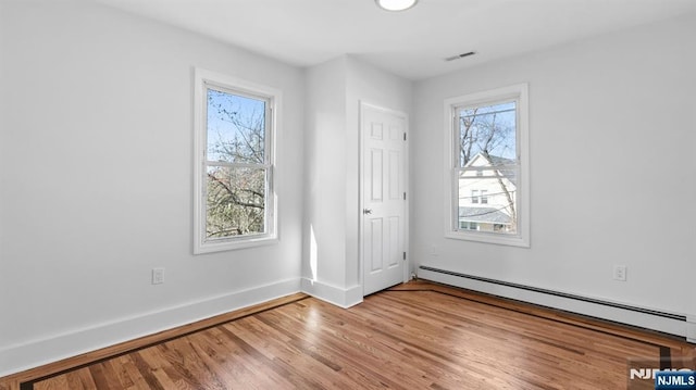unfurnished bedroom with baseboards, a baseboard radiator, light wood-style flooring, and visible vents
