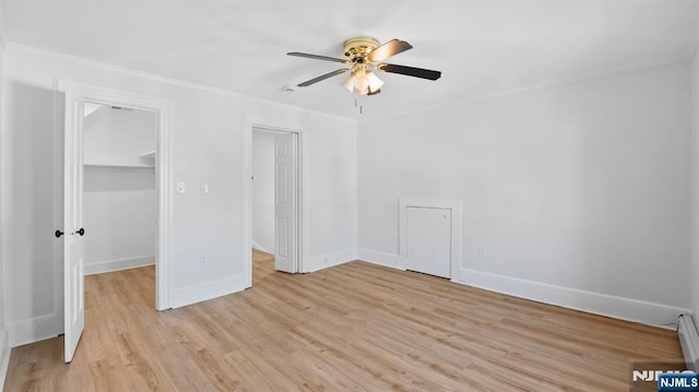 unfurnished bedroom with crown molding, baseboards, light wood-style flooring, and a spacious closet