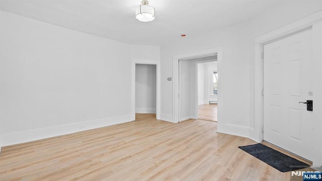 spare room with baseboards and light wood-style flooring