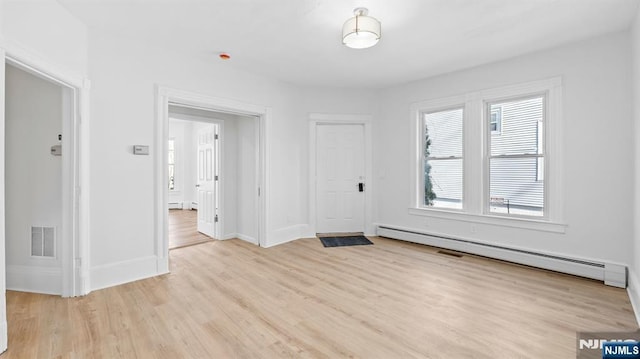 unfurnished room with visible vents, baseboard heating, baseboards, a baseboard radiator, and light wood-style flooring