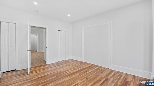 unfurnished bedroom with light wood-style floors, multiple closets, and recessed lighting