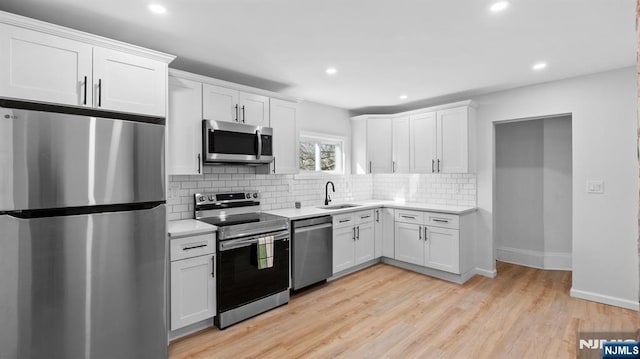 kitchen featuring light countertops, white cabinets, a sink, backsplash, and stainless steel appliances