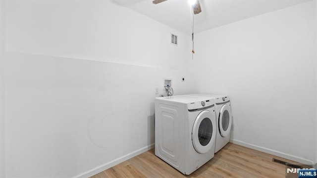 clothes washing area featuring washing machine and clothes dryer, laundry area, visible vents, and light wood-type flooring