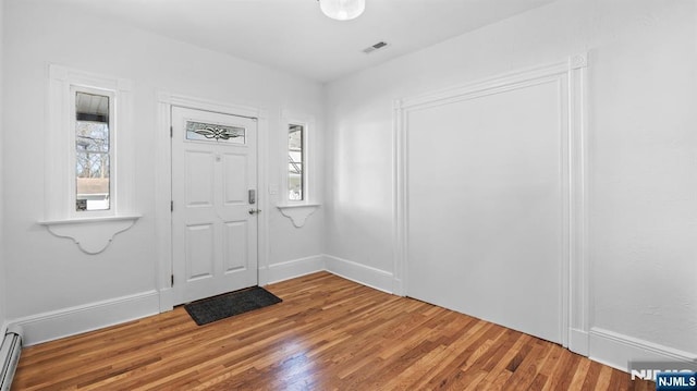 foyer entrance featuring visible vents, wood finished floors, and a wealth of natural light