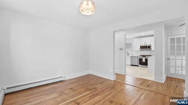 interior space featuring baseboards, baseboard heating, and light wood-style floors