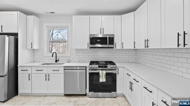 kitchen featuring appliances with stainless steel finishes, a sink, light countertops, white cabinetry, and visible vents