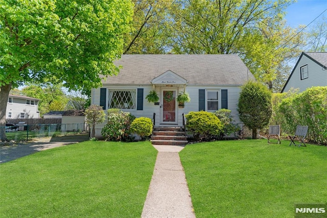 bungalow-style house with fence and a front lawn