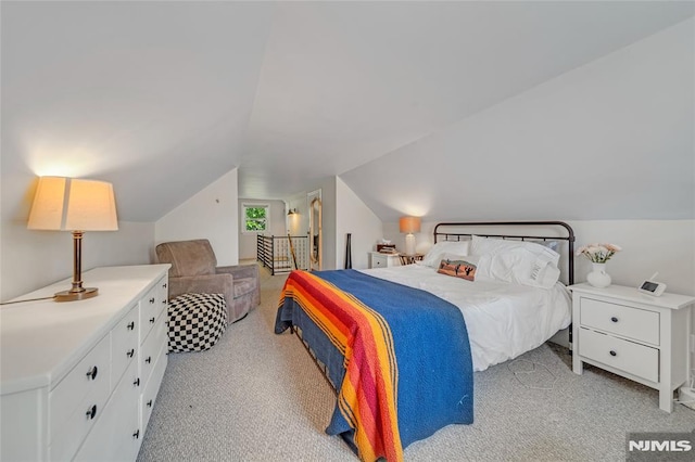 bedroom with light colored carpet and lofted ceiling